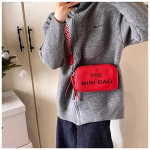 Detail of red textured leather mini bag with geometric strap and The Mini Bag lettering