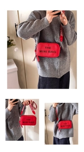 Detail of red textured mini bag with wide patterned strap and THE MINI BAG print