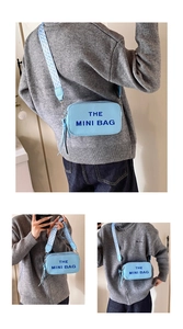Close-up of light blue leather camera bag with The Mini Bag text and wide strap
