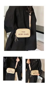 Detail of beige mini crossbody bag with embossed THE MINI BAG text and wave pattern strap