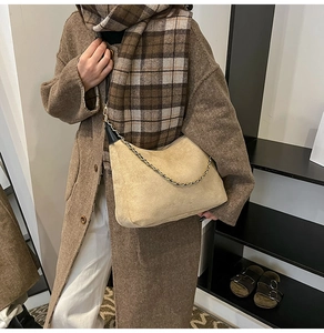 Détail du sac à bandoulière en daim beige avec chaîne dorée et lanière noire sur modèle