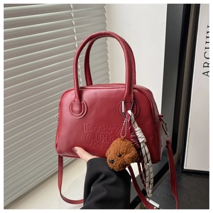 Detail of red leather Boston bag featuring artistic embossing and plush teddy pendant