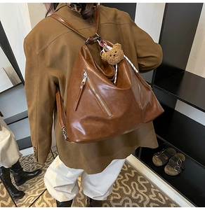 Détail d'un sac à dos vintage marron avec zips métalliques et breloque petit ours
