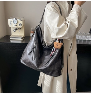 Détail d'un grand sac cabas vintage en cuir noir avec zip argenté et charm ours