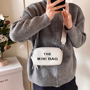 Chic white mini crossbody bag with black lettering and geometric patterned shoulder strap