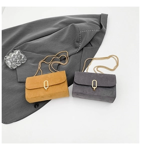 Detail of suede crossbody bags with elegant metal chain straps and oval gold buckle closures