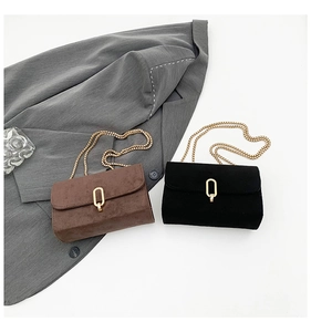 Detail of dark brown and black matte crossbody bags with golden oval twist locks and chains