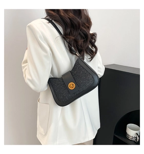 Detail of black glitter shoulder bag with gold clasp shown on a model