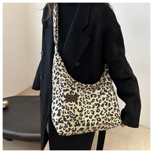 Detail of leopard print corduroy tote bag with fashion label on black wool coat