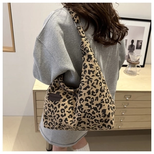 Detailed texture of leopard print corduroy tote bag with fashion label on shoulder strap