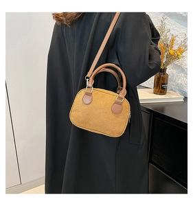 Detail showing mustard yellow suede pillow bag with brown leather handles on a black coat