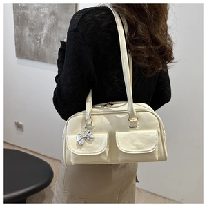 Dettaglio borsa bowling color crema con tasche cargo e ciondolo a fiocco argentato