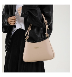 Detail of light beige PU leather bag with gold buckle and knotted shoulder strap