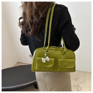 Detail der avocadogrünen Bowlingtasche mit Pattentaschen und silbernem Schleifenanhänger