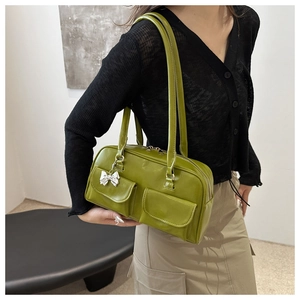 Dettaglio borsa a mano verde avocado in finta pelle con doppie tasche e ciondolo a fiocco argento