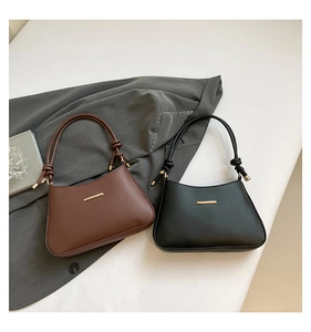 Detail of brown and black leather underarm bags with gold buckles and knotted straps