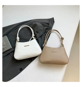 Detail view of leather shoulder bags in cream and beige with sleek gold bar accents