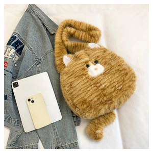 Detailed top view of a ginger cat plush crossbody bag next to a tablet and jacket