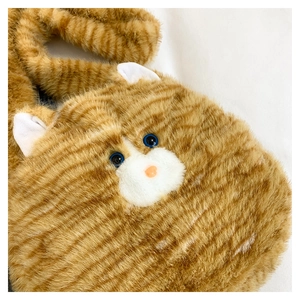 Close-up of orange tabby cat plush bag showing fuzzy texture and realistic blue eyes