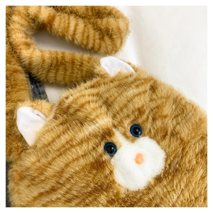 Detail of orange tabby plush cat bag featuring blue 3D eyes and soft faux fur texture