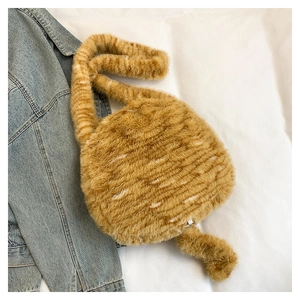 Close-up of fluffy orange tabby plush crossbody bag on denim background with soft tail detail