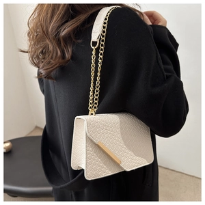Detail of cream woven pattern chain bag showing gold metal trim and leather strap