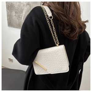 Close-up of white woven leather crossbody bag with gold chain strap on black coat