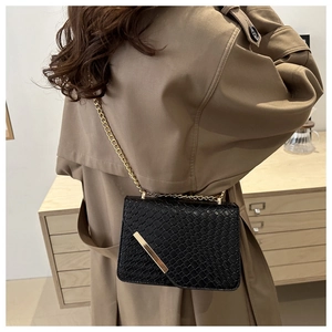 Model wearing a black woven leather crossbody bag with elegant gold chain and hardware detail