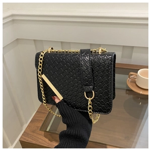 Detail of black woven texture crossbody bag with gold chain strap and metal clasp