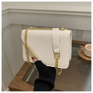 Close-up of white woven leather texture on small flap bag with gold chain strap
