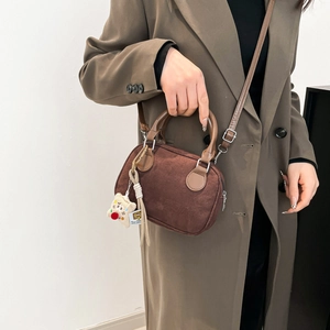 Vintage dark brown suede bowling bag with white plush bear charm on model in trench coat
