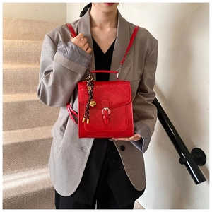 Close-up of a red vintage handbag with a decorative bell charm and crossbody strap