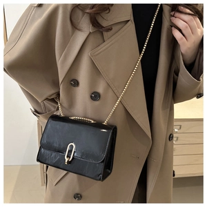 Close-up of black patent leather crossbody bag with gold lock and chain strap