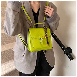 Close-up of bright green glossy leather mini backpack with a stylish woven bell charm
