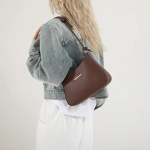 Brown minimalist underarm shoulder bag with knotted strap and gold hardware on model