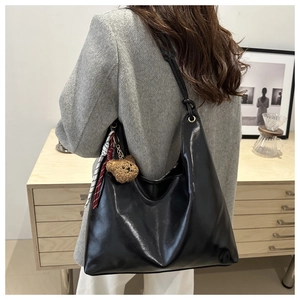 Détail d'un sac cabas noir brillant avec pendentif ours et ruban rayé décoratif