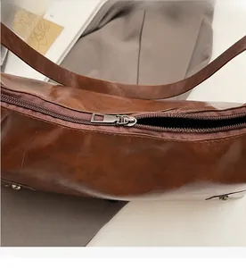 Detailed close-up of smooth silver-tone metal zipper on brown textured leather tote bag