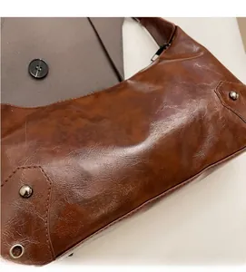Detail shot of brown vintage faux leather tote with rivet accents and oily crackle texture