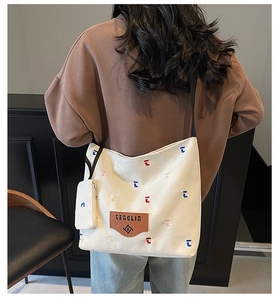 Detail of canvas tote bag with brown leather logo patch and mini hanging pouch