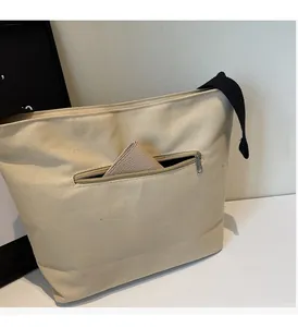 Detail of the front zipper pocket on a canvas tote bag showing storage for a wallet