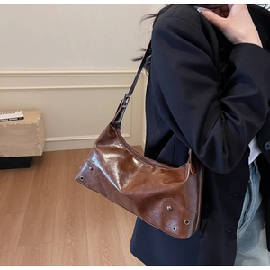 Detail of vintage brown oil-wax leather shoulder bag with metallic eyelets and studs