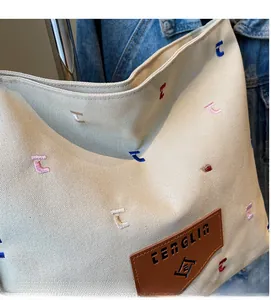 Detail of cream canvas tote showing the colorful letter C embroidery and leather patch