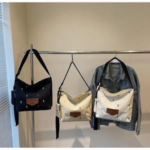 Three canvas tote bags in black, beige, and white with colorful letter embroidery details