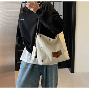Detail of canvas bucket bag with letter embroidery and brown leather logo patch