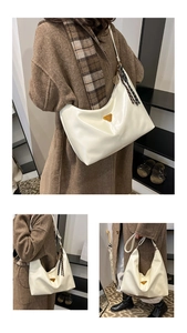 Detail of cream white leather tote bag with iconic triangle logo and scarf charm