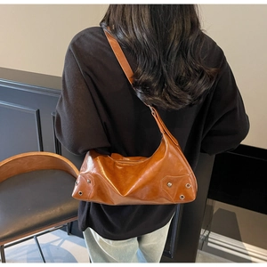 Dettaglio borsa hobo in pelle lucida marrone con rivetti e tracolla regolabile