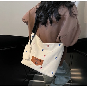 Detail of canvas tote bag with colorful embroidery and a small zipper pouch accessory