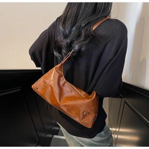 Detail of vintage brown leather shoulder bag featuring metal studs and grommet accents