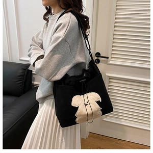 Retro black corduroy drawstring tote bag with cute dog embroidery on a female model