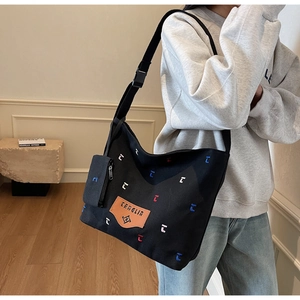 Detail of black canvas bucket bag with wide strap, mini coin pouch and colorful embroidery